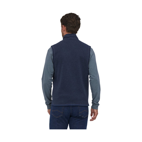 Back view of a navy fleece vest worn over a gray long-sleeve shirt