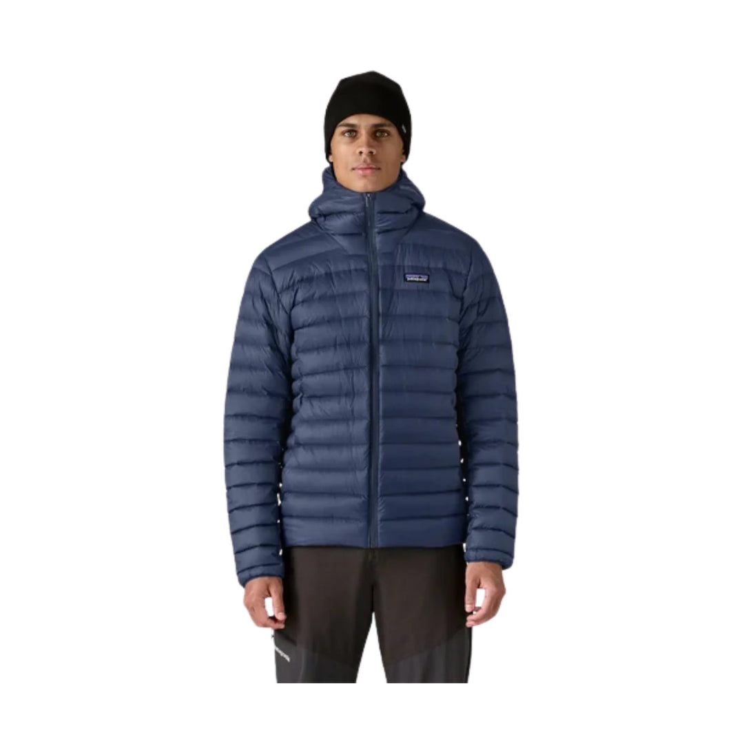 Navy hooded puffer jacket with front zipper, worn over black pants