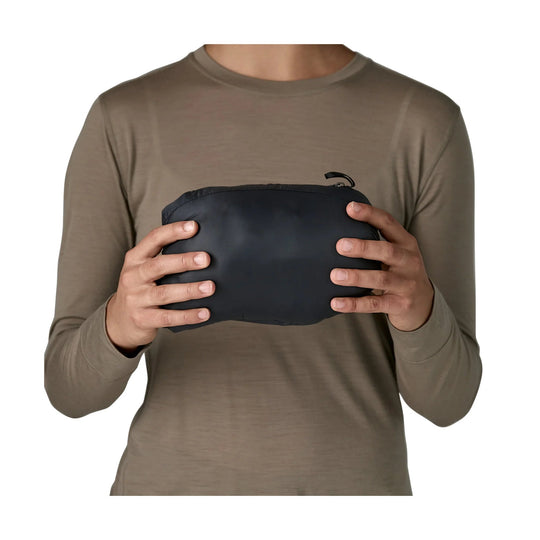 Person holding a black zip pouch while wearing a taupe long-sleeve shirt