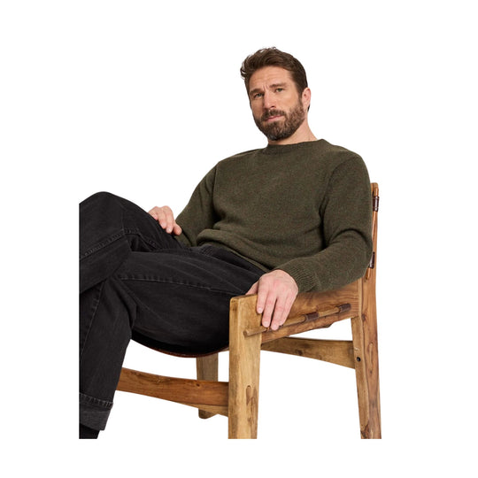 Olive green crewneck sweater on a seated man with black jeans