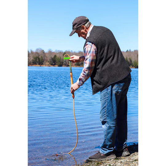 Orange extension hose with green connector, held over a lake by a man standing on the shore