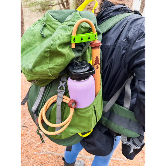 Coiled tan extension hose attached to a green backpack with a purple water bottle