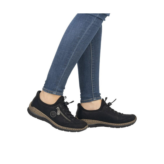 Black slip-on sneakers with laces, side zipper, and tan textured midsoles on blue jeans