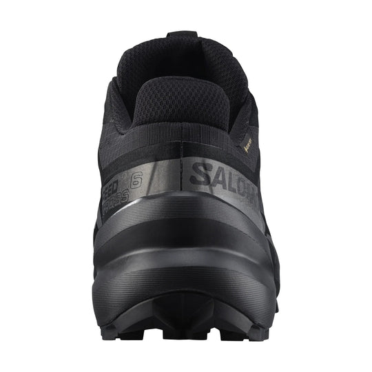 Black trail running shoe shown from the heel with textured upper and lugged sole