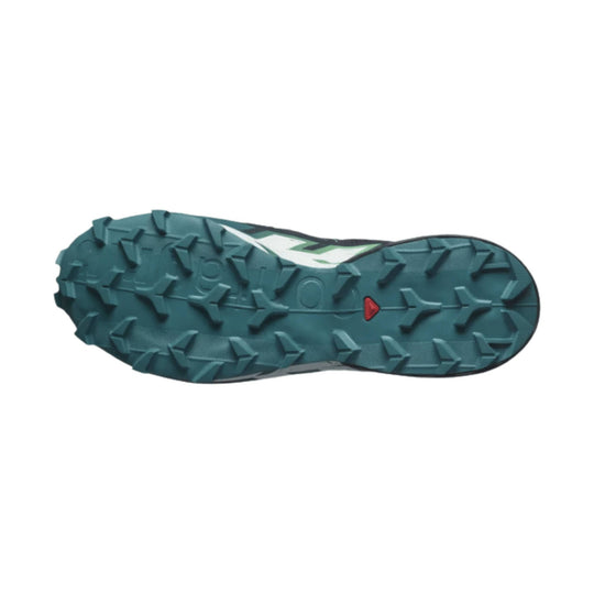 Blue-green trail running shoe outsole with aggressive lugs and a small red accent