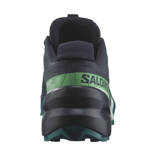 Back view of a dark trail running shoe with a green heel band and lugged sole