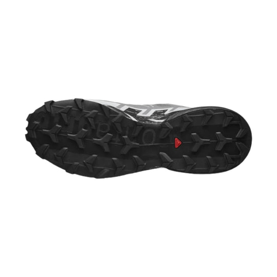 Black trail shoe outsole with deep lug tread and a small red triangular mark