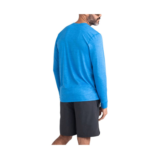 Model wearing a blue long-sleeve crewneck top and black shorts, shown from the back