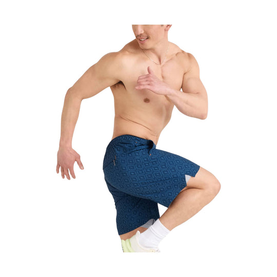 Man modeling blue patterned athletic shorts with built-in black compression shorts