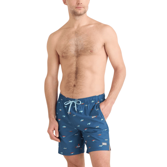 Blue swim trunks with small multicolor boat print and drawstring waist, worn by a male model