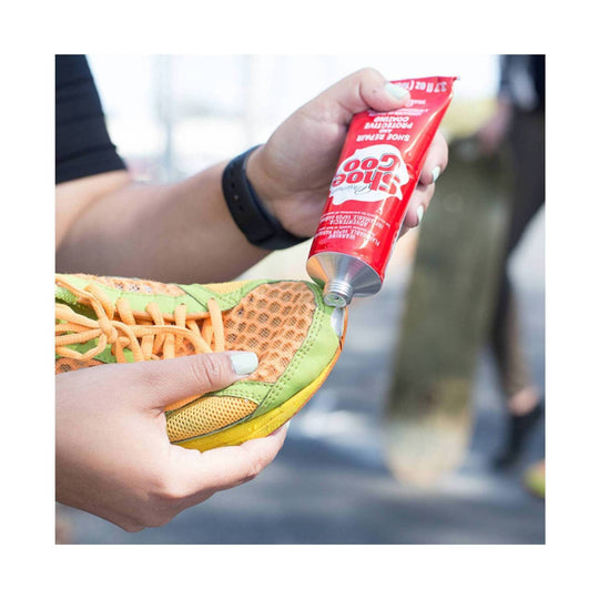 Person applying a tube of Googoo shoe glue to a shoe.