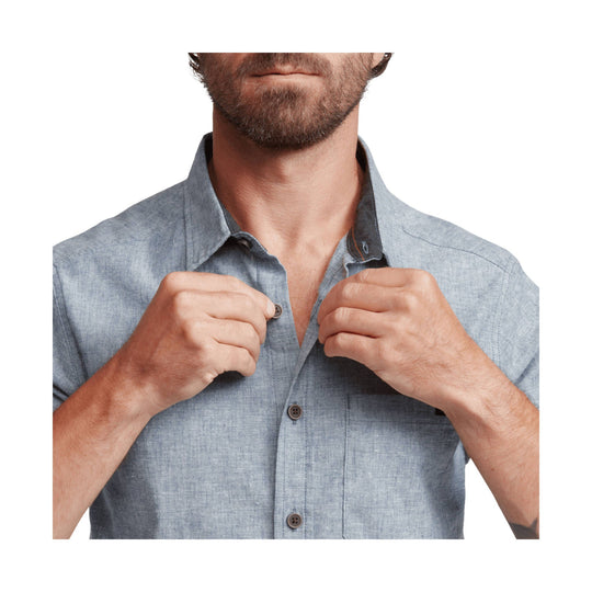 Light blue short-sleeve button-up shirt worn by a man, shown from chest to neck while he holds the collar open