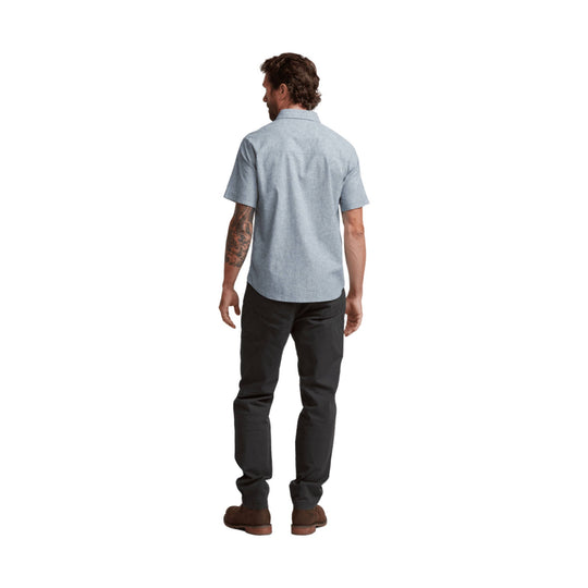 Light blue short-sleeve button-up shirt shown from the back with dark pants and brown shoes