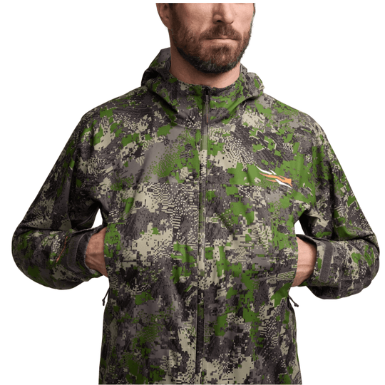 Camouflage hooded zip-up jacket with front pockets and a small chest logo on a model.