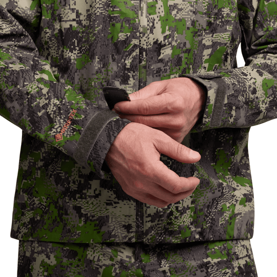 Camouflage zip-front jacket with Velcro cuffs and GORE-TEX sleeve logo, shown with hands folded in front