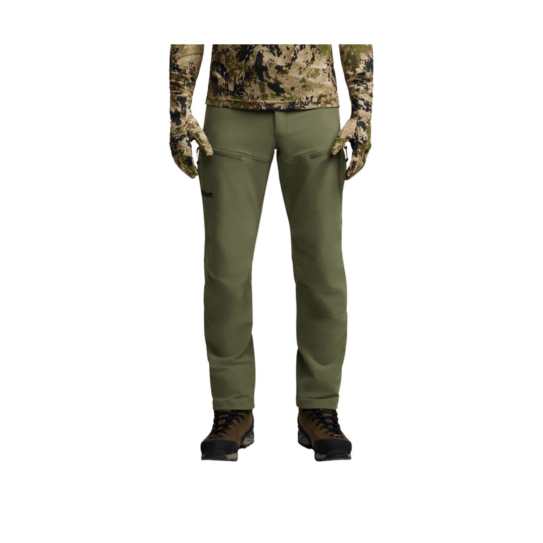 Olive green hiking pants with zip thigh pockets, shown on a model from waist to boots