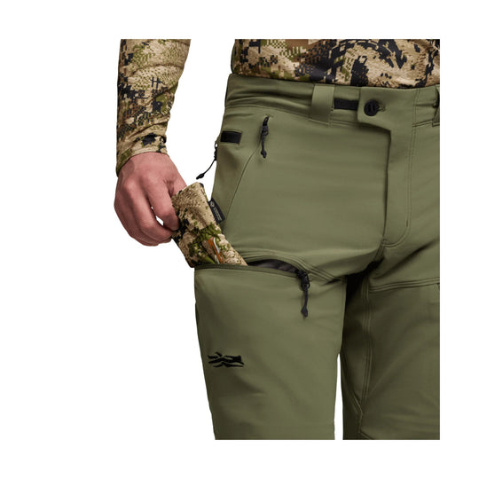 Olive green men's pants with zippered thigh pockets and camo-print paneling