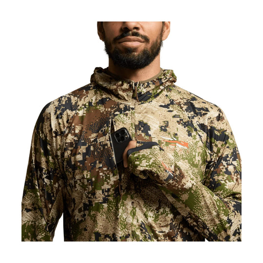 Camo hooded zip-up performance top with hand covering a phone at the chest