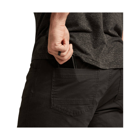 Black five-pocket pants shown from the back, with a hand in the rear pocket.