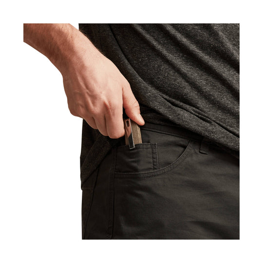 Man wearing dark pants with a front hand pocket and zipper pull