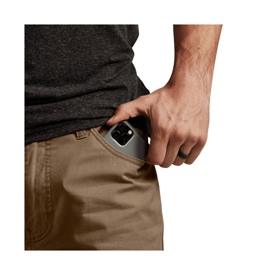 Man wearing brown pants with a hand in the front pocket holding a smartphone