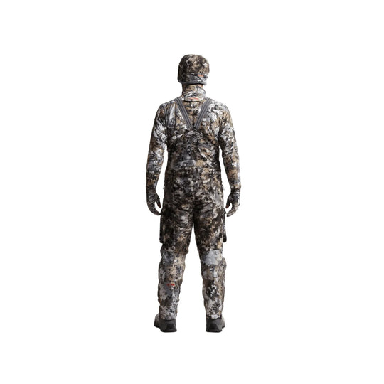 Camouflage hunting bib seen from the back with matching hood, gloves, and boots