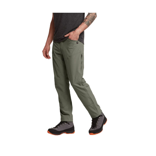 Olive green men’s hiking pants with zippered thigh pocket, shown with boots