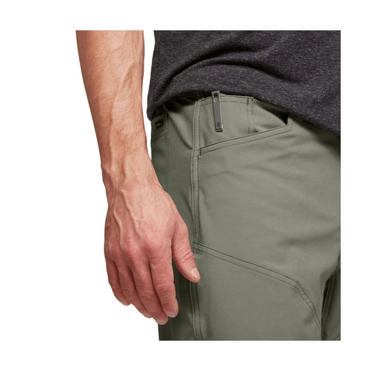 Olive green men’s pants with stitched pocket details and a small hanging zipper pull