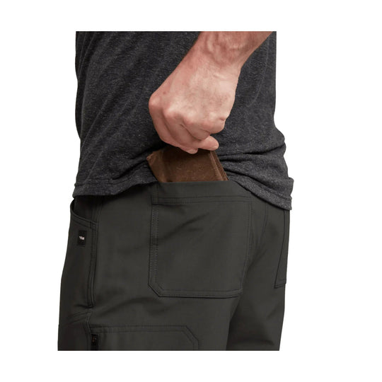 Man placing a brown wallet into the back pocket of dark pants