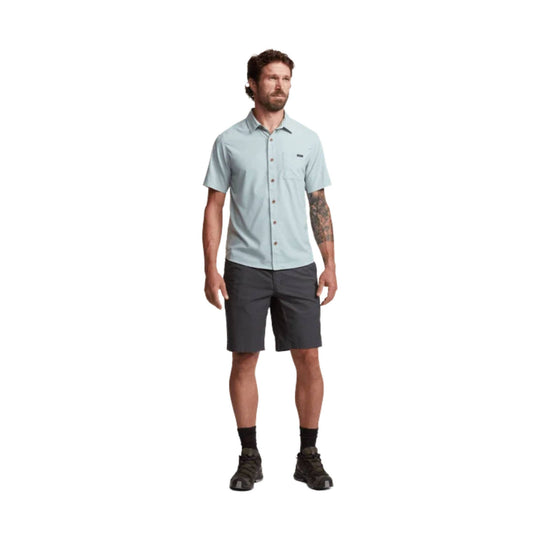 Light blue short-sleeve button-up shirt with chest pocket, worn with dark shorts
