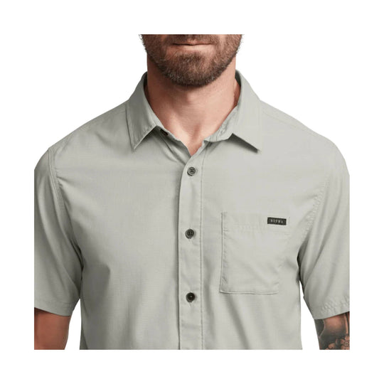 Light gray short-sleeve button-up shirt with chest pocket and small front logo patch