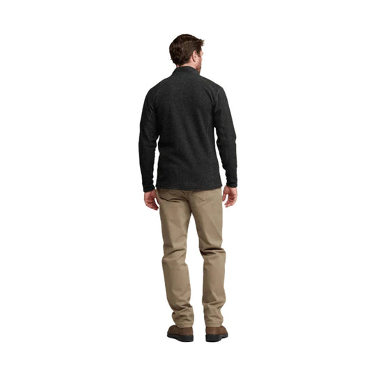 Man wearing a dark quarter-zip fleece pullover with khaki pants, shown from the back