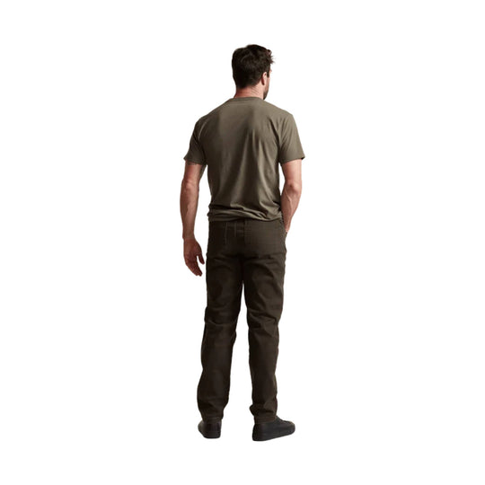 Man wearing olive short-sleeve T-shirt and dark pants, shown from the back