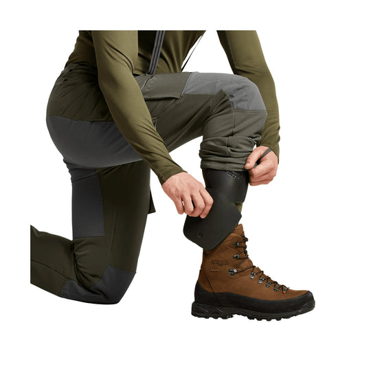 Olive and gray hiking pants with reinforced knee panels, shown with a cuff being adjusted over a boot