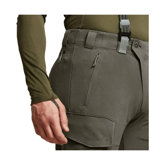 Olive outdoor pants with suspenders, zippered thigh pockets, and a side cargo pocket