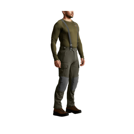 Olive hiking pants with suspenders, reinforced knees, and zip cargo pockets on a standing male model
