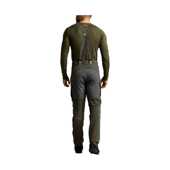 Olive and gray hiking pants with suspenders, shown from the back on a model