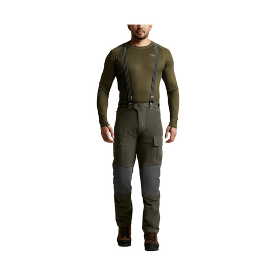 Olive cargo pants with suspenders, reinforced knees, and brown hiking boots