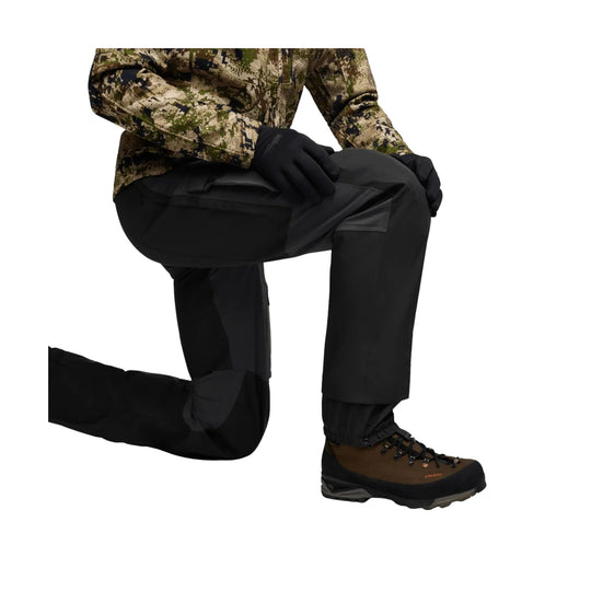 Camouflage hunting pants with black gloves and brown hiking boots