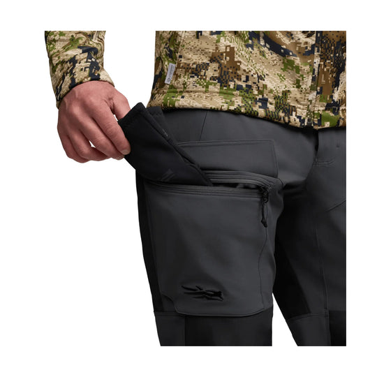 Black technical pants with a zippered thigh pocket, shown with the pocket open.