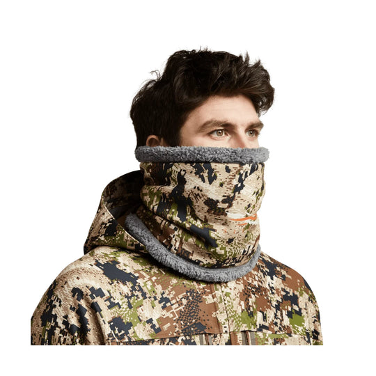 Camouflage neck gaiter and hooded jacket with gray fleece trim, worn by a male model