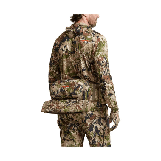 Camouflage hunting belt with front pouch and attached rolled seat pad, worn over matching camo clothing