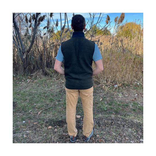 Black fleece vest worn over a light blue short-sleeve shirt, shown from the back