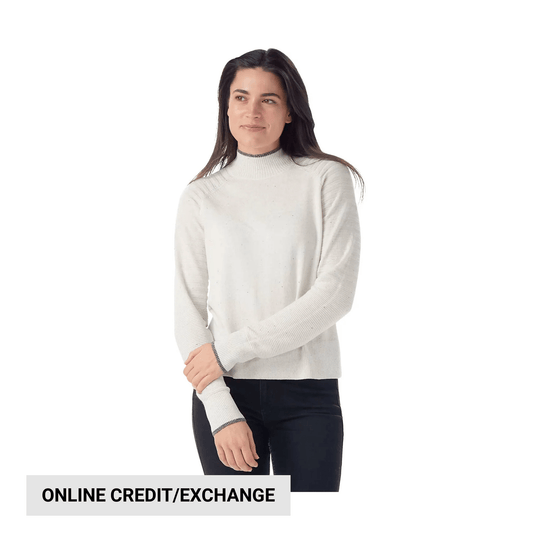 Woman wearing a white mock neck sweater with ribbed cuffs and black pants, with an ONLINE CREDIT/EXCHANGE sign.