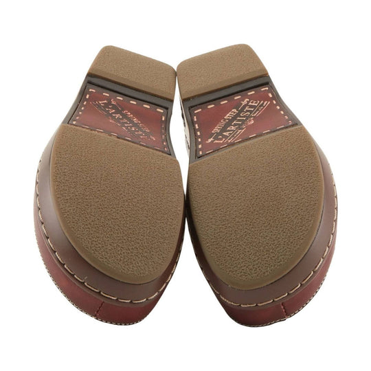 Pair of brown clog outsoles with textured tan tread and visible L'Artiste branding