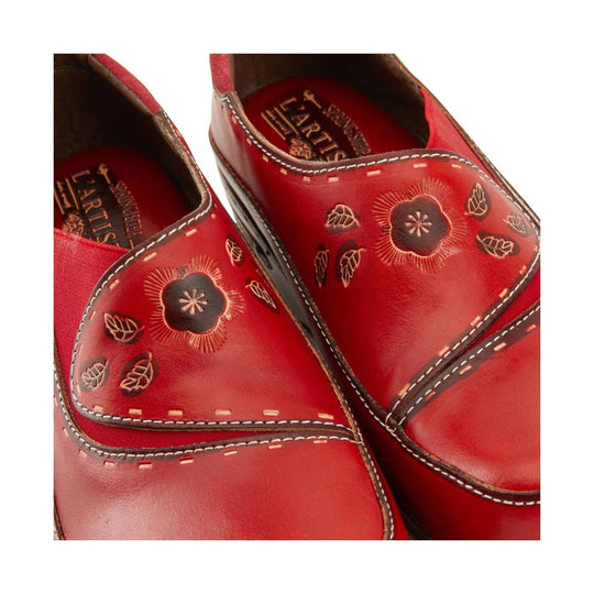 Red leather clogs with floral cutout detailing and visible brand text inside
