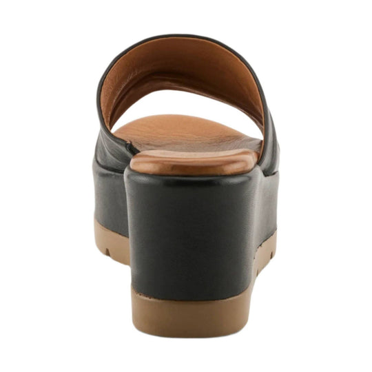 Black heeled wedge sandal viewed from the back with tan footbed and sole