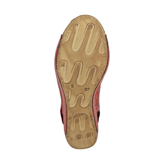 Tan outsole of a women’s sandal with molded tread and red side upper