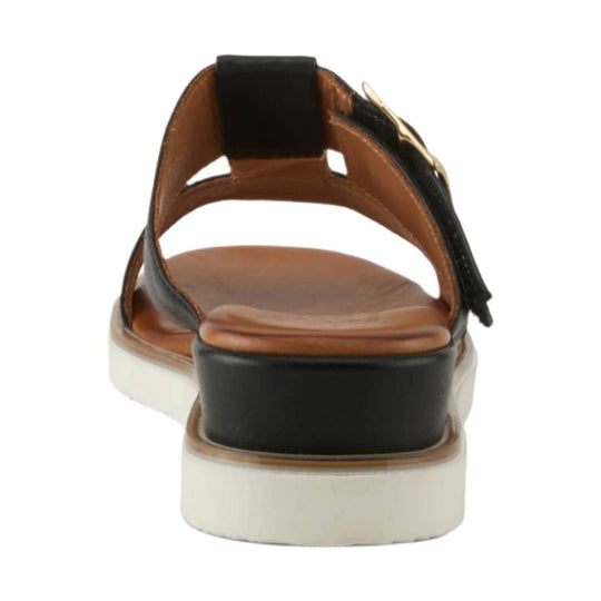 Black strappy sandal viewed from the back with tan footbed, white platform sole, and gold buckle