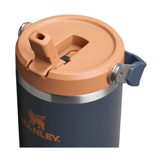 Dark insulated tumbler with peach lid, side handle, and visible Stanley logo